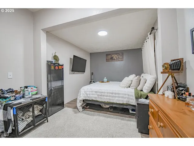 a bedroom with a bed and a flat tv screen on the dresser