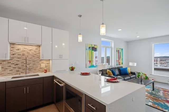 a kitchen with a sink dishwasher a stove and white cabinets with wooden floor