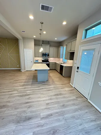 a view of kitchen with kitchen island a sink wooden floor and a counter top space