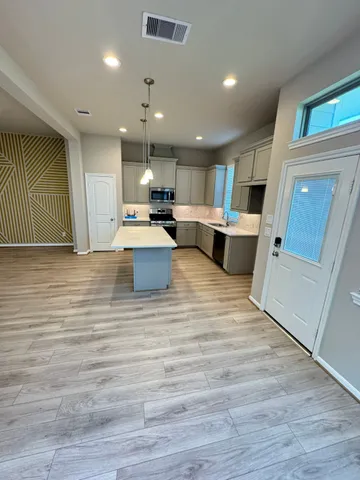 a view of kitchen with kitchen island a sink wooden floor and a counter top space
