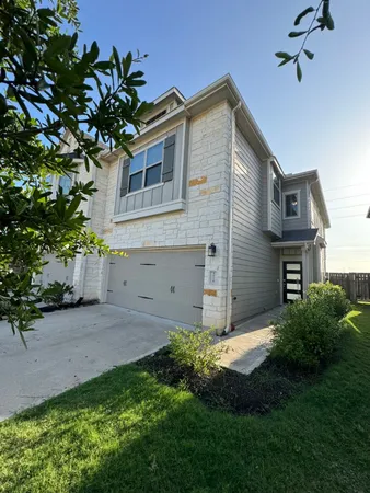 a view of a house with a small yard and a large tree