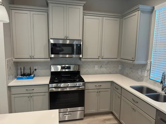 a kitchen with white cabinets and black appliances