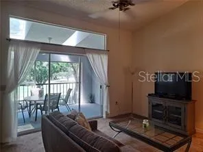a living room with furniture a flat screen tv and a floor to ceiling window