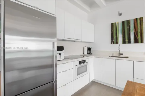 a kitchen with a sink dishwasher stove and white cabinets with wooden floor
