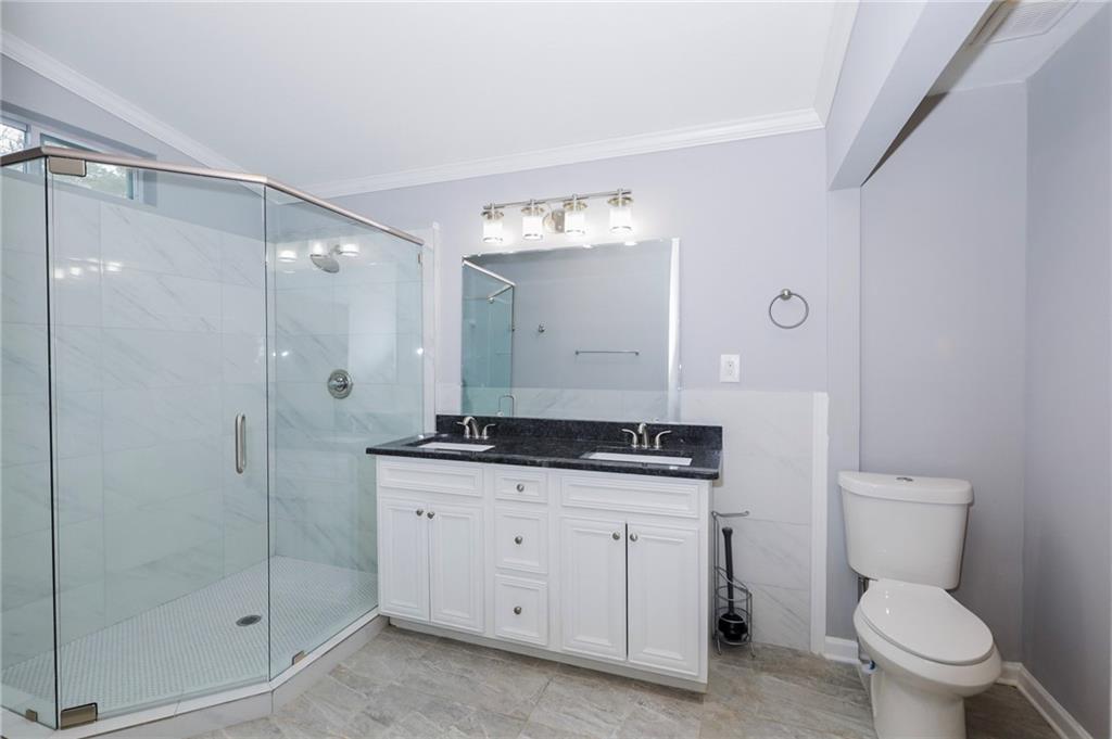 1277 Goodwin Road Northeast, Unit 1273 Atlanta, GA 30324 - Photo 14 of 18 a bathroom with a granite countertop sink a toilet a mirror and shower
