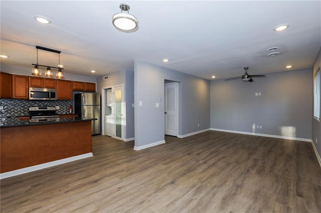 1277 Goodwin Road Northeast, Unit 1273 Atlanta, GA 30324 - Photo 6 of 18 an empty room with wooden floor and kitchen view
