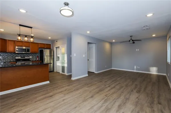an empty room with wooden floor and kitchen view