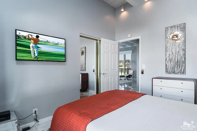 a bedroom with a bed and a flat tv screen on dresser