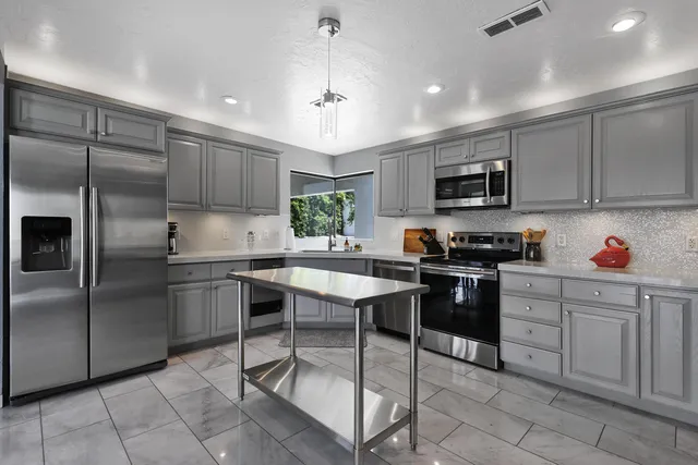 a kitchen with kitchen island granite countertop a stove sink microwave and refrigerator
