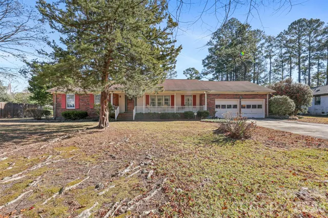 a front view of a house with a yard covered with snow and trees