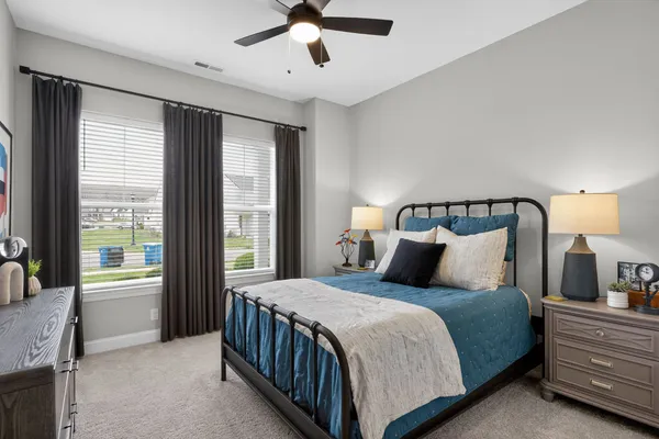 a bedroom with a large bed and a chandelier fan