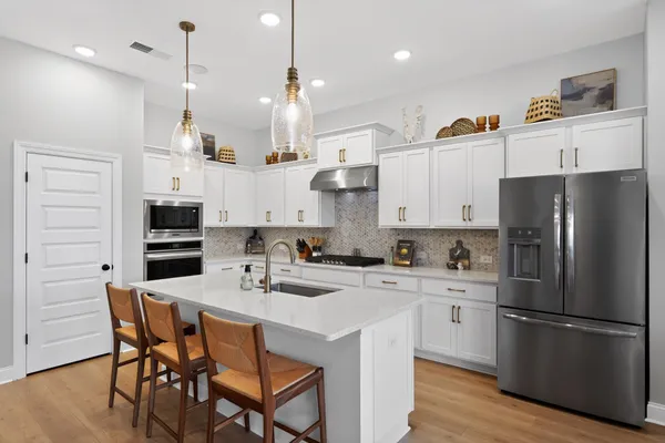 a kitchen with stainless steel appliances kitchen island a refrigerator a stove a sink a dining table and chairs