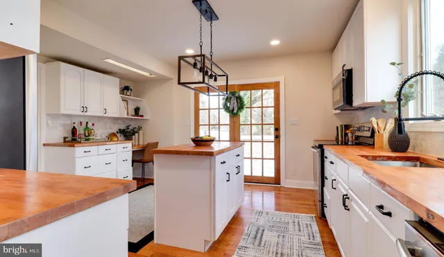 a kitchen that has a lot of cabinets in it and wooden floors