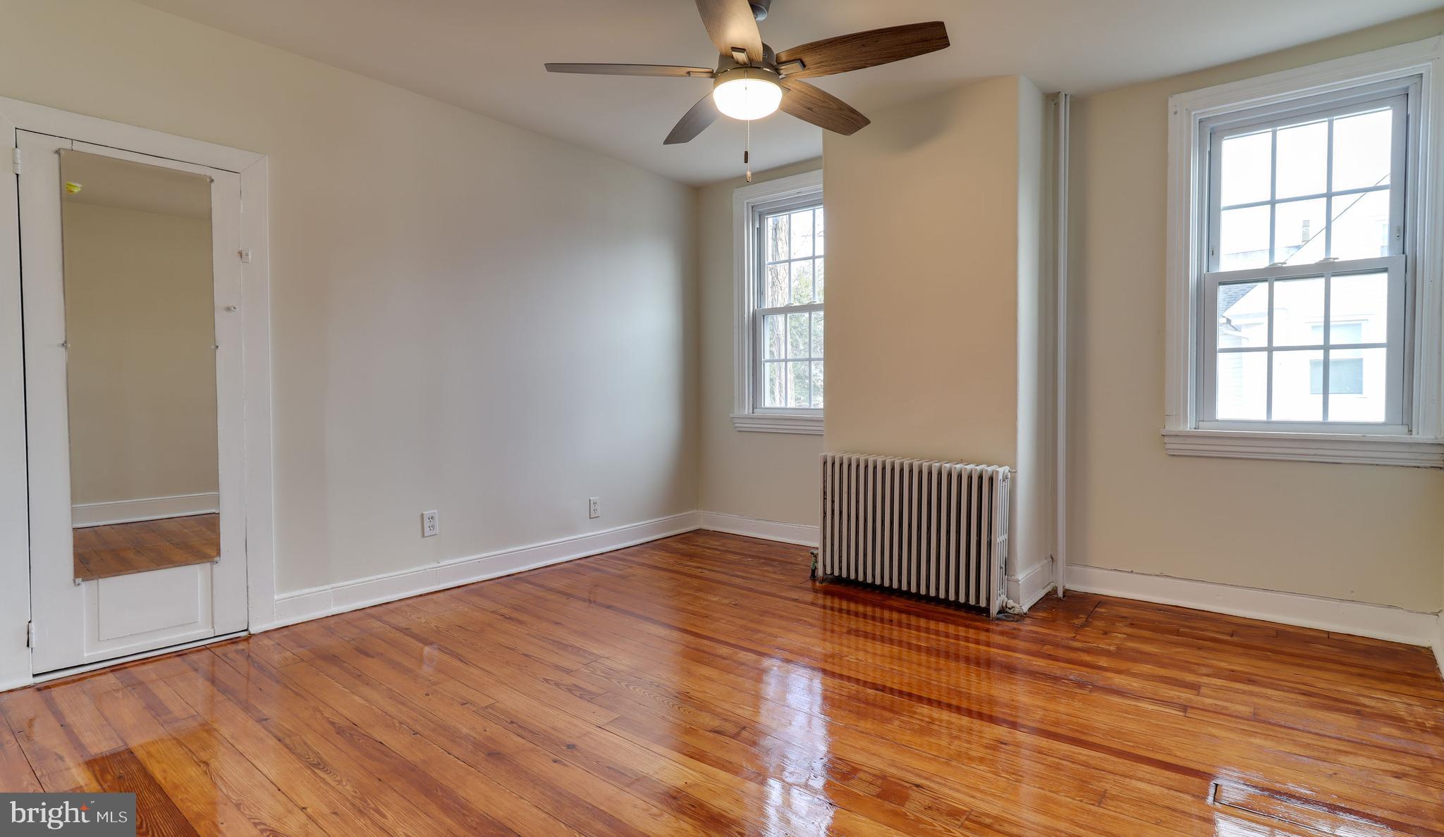161 Warren Street Beverly, NJ 08010 - Photo 16 of 31 an empty room with wooden floor chandelier fan and windows