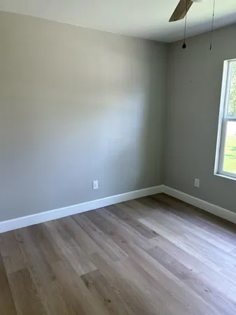 a view of an empty room with wooden floor and a window