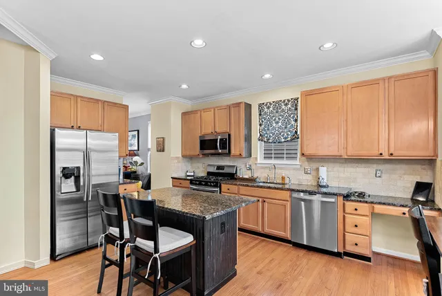 a kitchen with stainless steel appliances granite countertop a stove top oven a sink dishwasher and cabinets with wooden floor