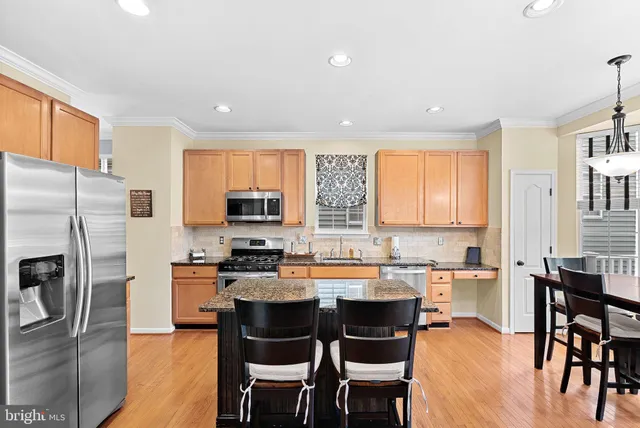 a kitchen with a sink a stove a refrigerator cabinets and dining table