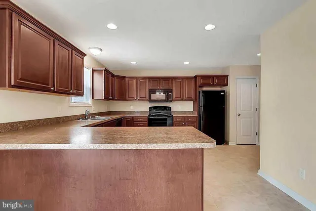 a large kitchen with stainless steel appliances granite countertop a refrigerator a sink a stove and a microwave oven on granite countertops