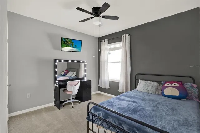 a bedroom with a bed a desk and chair with the potted plants