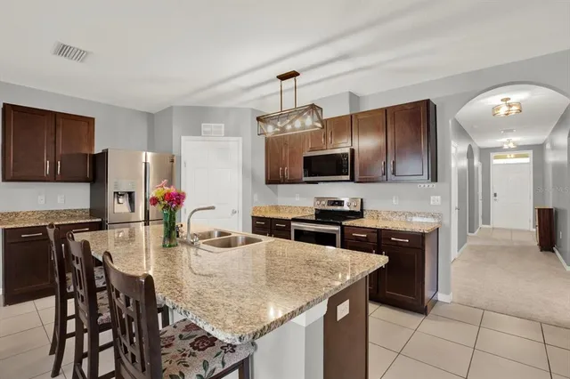 a kitchen with stainless steel appliances granite countertop a stove top oven a sink dishwasher a dining table and chairs with wooden floor