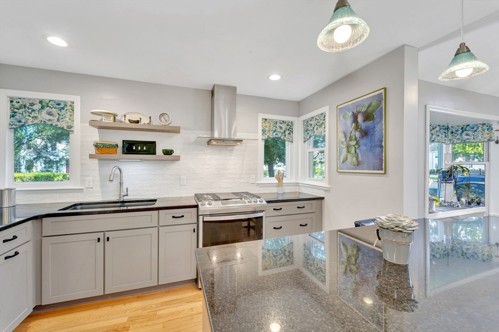 4 Rebecca Road Newton, MA 02465 - Photo 6 of 39 a kitchen with stainless steel appliances granite countertop a stove top oven a sink a dining table and chairs with wooden floor