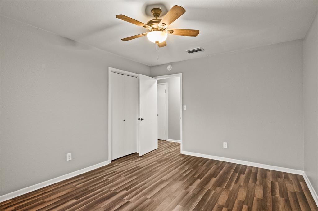 231 Quitman Street Pittsburg, TX 75686 - Photo 23 of 32 a view of an empty room with window a chandelier fan and wooden floor