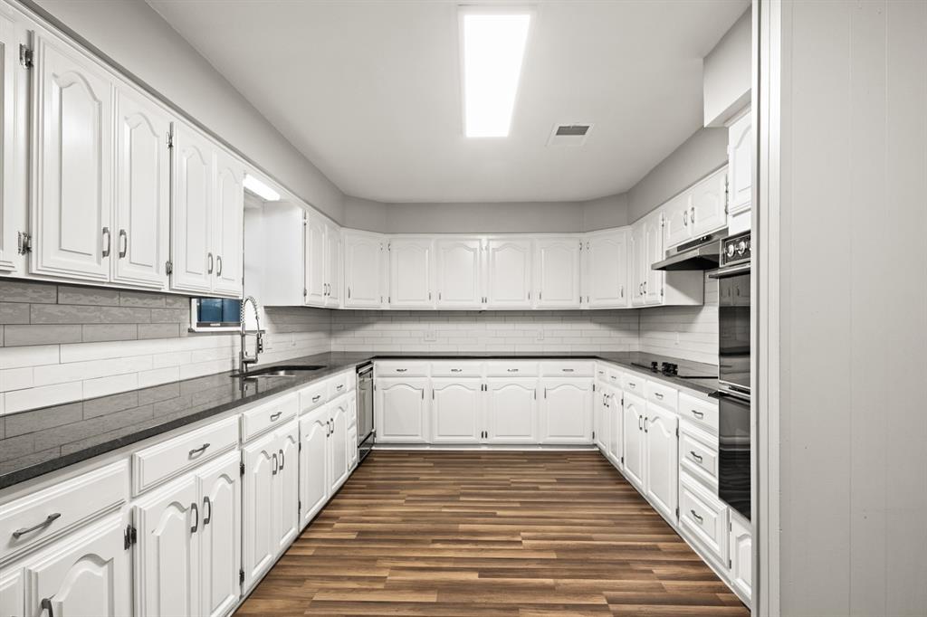 231 Quitman Street Pittsburg, TX 75686 - Photo 10 of 32 a kitchen with granite countertop a sink and dishwasher a stove top oven with white cabinets