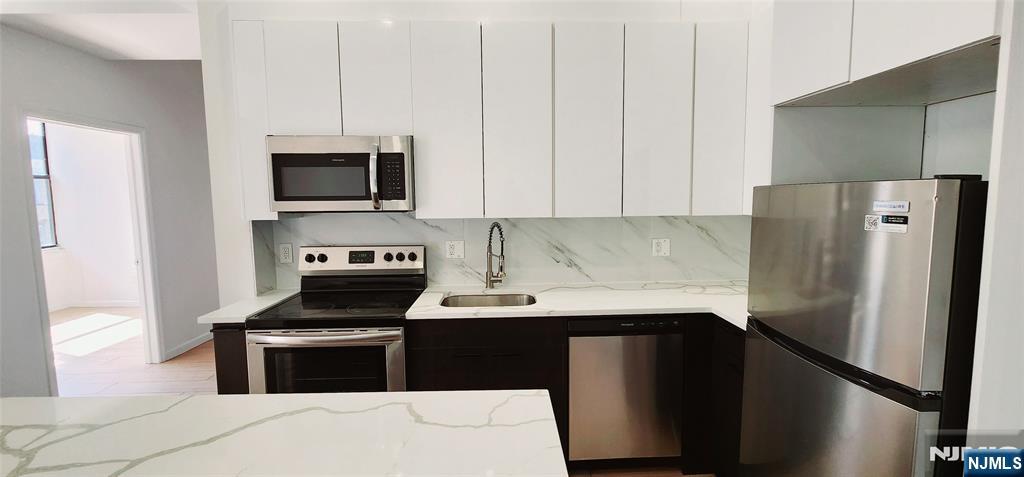 30 Howe Avenue, Unit 301 Passaic, NJ 07055 - Photo 6 of 10 a kitchen with stainless steel appliances a stove microwave and refrigerator