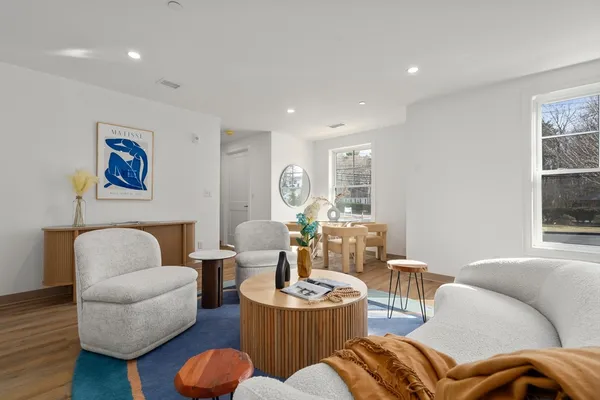 a living room with furniture kitchen view and a window