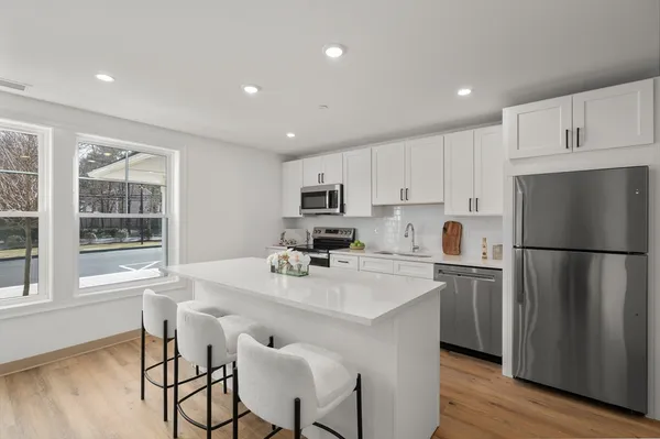 a kitchen with a refrigerator a stove a sink and white cabinets with wooden floor