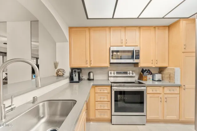 a kitchen with stainless steel appliances a stove a sink a refrigerator and cabinets