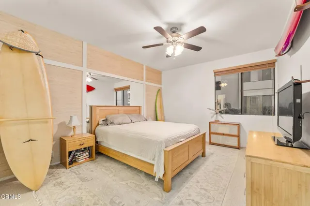 a spacious bedroom with a bed a dresser and flowerpot