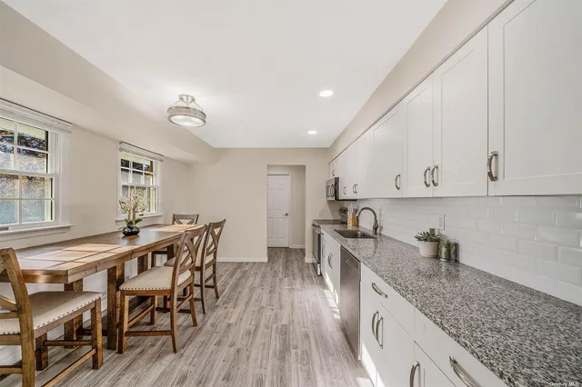 a kitchen with stainless steel appliances granite countertop a table chairs sink and cabinets