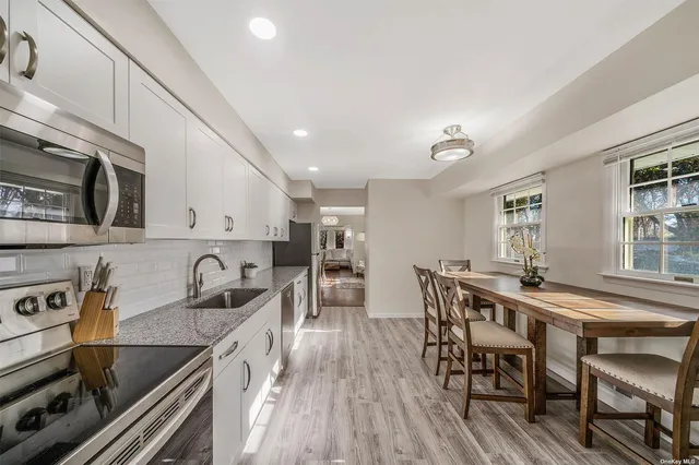 a kitchen with stainless steel appliances granite countertop a stove top oven a sink a dining table and chairs with wooden floor