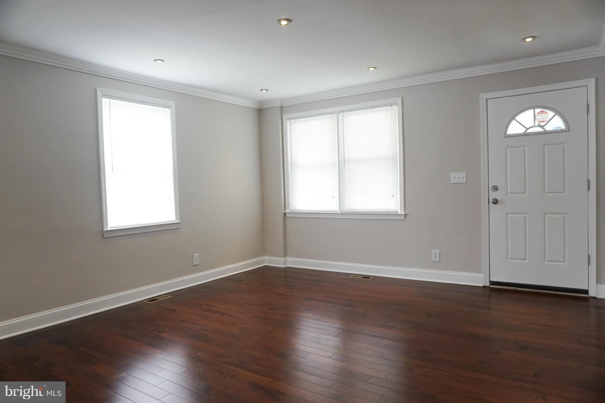 901 Wicklow Road Baltimore, MD 21229 - Photo 4 of 29 a view of an empty room with wooden floor and a window