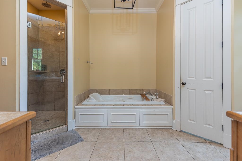 1915 Teague Store Road Somerville, TN 38068 - Photo 30 of 38 Bathroom featuring a spacious walk-in shower with tile surround and glass enclosure, an integrated soaking tub with a tiled deck, and light-toned floor tiling