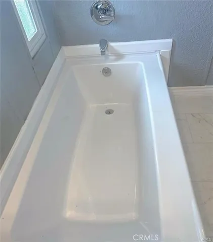 an empty room with wooden floor and kitchen view