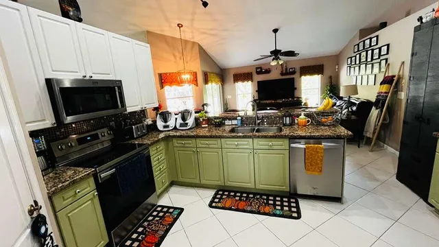 a kitchen with granite countertop a stove top oven a sink a counter top space and cabinets