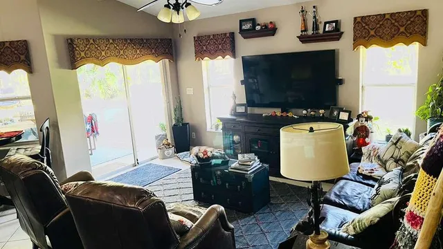 a living room with furniture a flat screen tv and a large window
