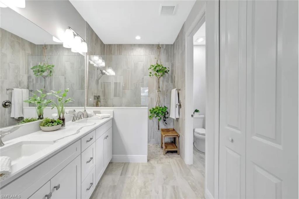 4621 Centaurus Circle Naples, FL 34120 - Photo 13 of 47 Bathroom featuring double vanity, tile walls, and a closet staged for photo