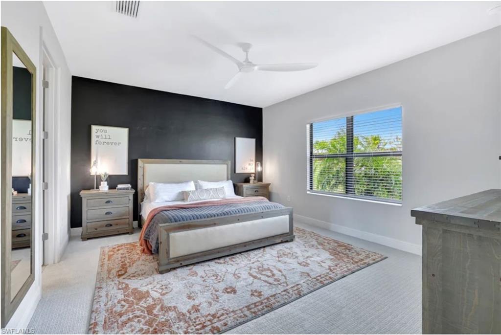4621 Centaurus Circle Naples, FL 34120 - Photo 14 of 47 Bedroom with an accent wall, a ceiling fan, and light colored carpet staged for photo
