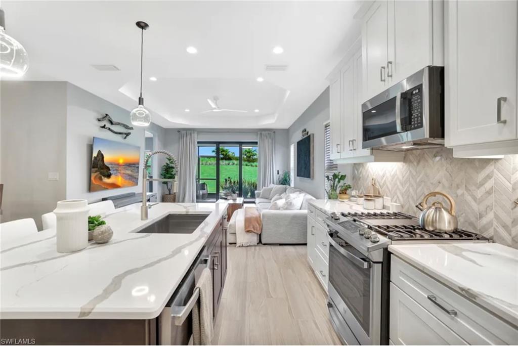 4621 Centaurus Circle Naples, FL 34120 - Photo 2 of 47 Kitchen featuring white cabinetry, appliances with stainless steel finishes, light stone counters, decorative light fixtures, and recessed lighting staged for photo