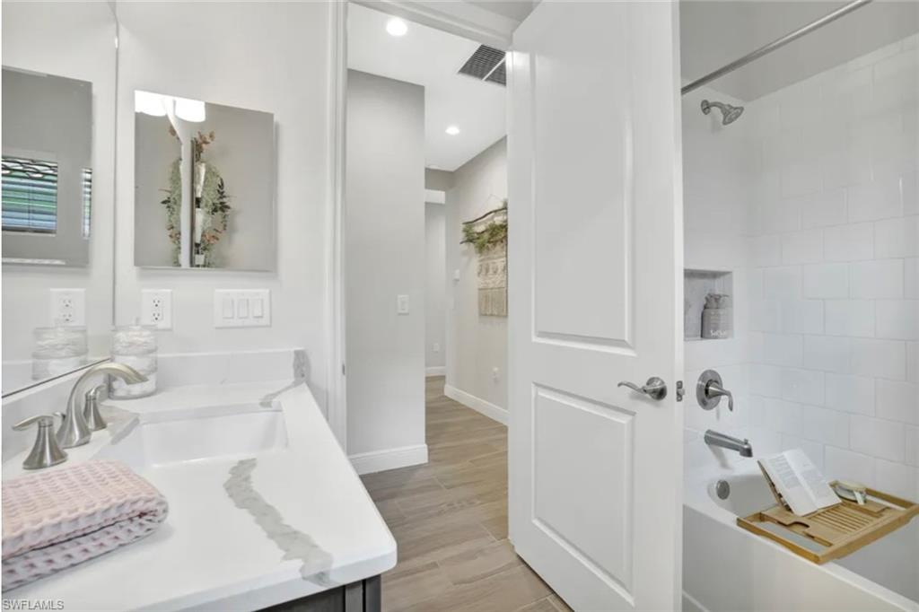 4621 Centaurus Circle Naples, FL 34120 - Photo 21 of 47 Full bath with washtub / shower combination, vanity, and wood finish tile floor staged for photo