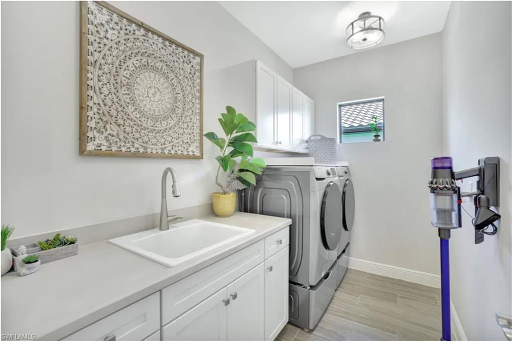 4621 Centaurus Circle Naples, FL 34120 - Photo 21 of 47 Laundry room featuring cabinet space, washing machine and dryer, and wood tiled floors staged for photo