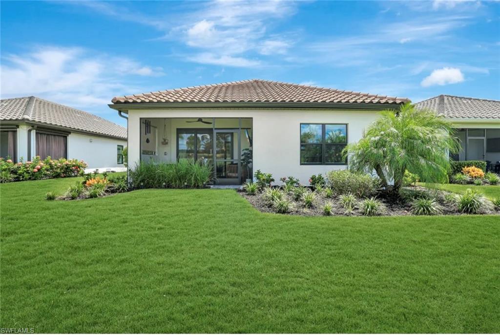 4621 Centaurus Circle Naples, FL 34120 - Photo 36 of 47 Back of house with a ceiling fan, a lawn, stucco siding, and a tile roof