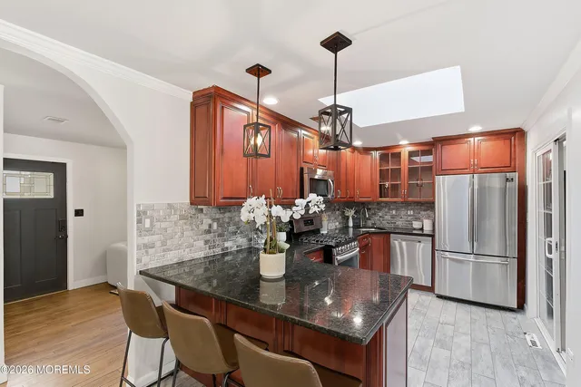 a kitchen with stainless steel appliances granite countertop a dining table and chairs