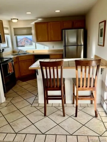 a kitchen with stainless steel appliances kitchen island granite countertop a refrigerator and a stove top oven