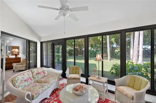 a living room with furniture large windows and a chandelier