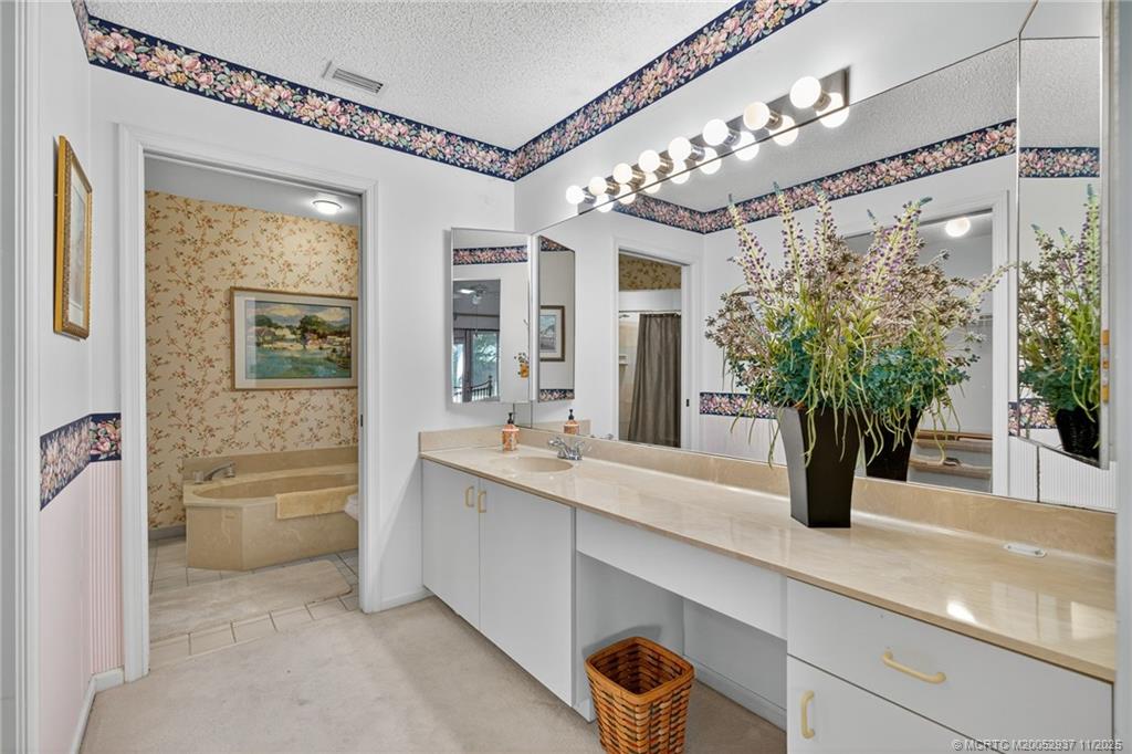 6001 Southeast Martinique Drive, Unit 104 Stuart, FL 34997 - Photo 23 of 36 a bathroom with a double vanity sink and a mirror