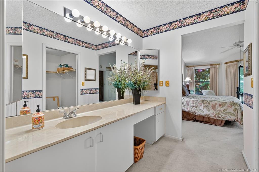 6001 Southeast Martinique Drive, Unit 104 Stuart, FL 34997 - Photo 24 of 36 a bedroom with a large bed and a chandelier